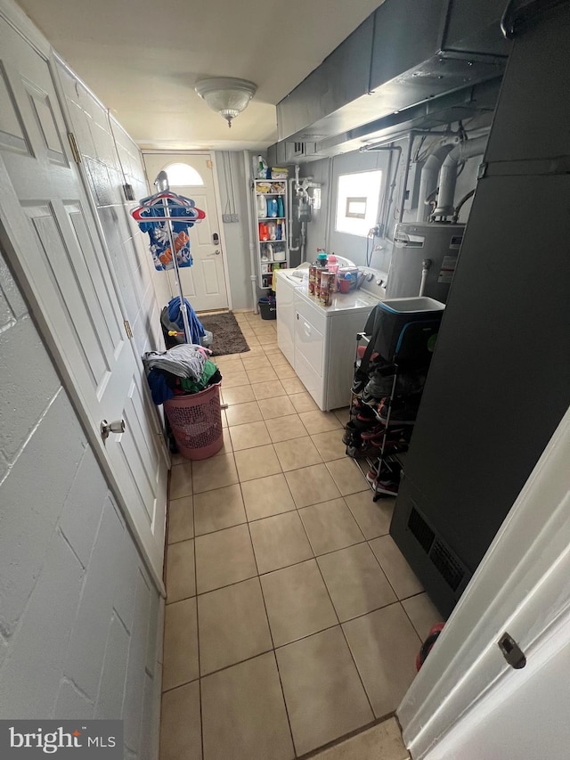laundry area featuring electric water heater, laundry area, light tile patterned flooring, and washing machine and clothes dryer