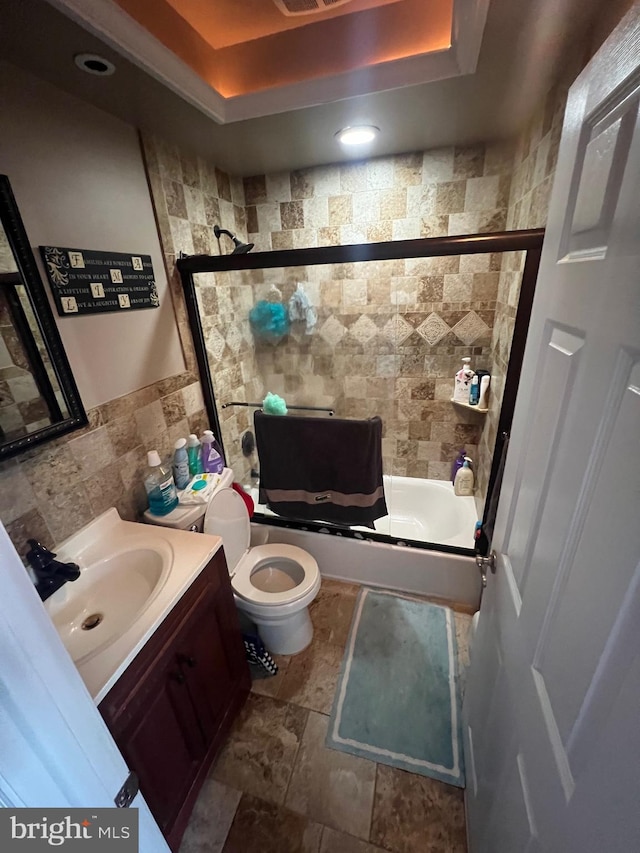 bathroom with visible vents, tile walls, vanity, toilet, and a tray ceiling