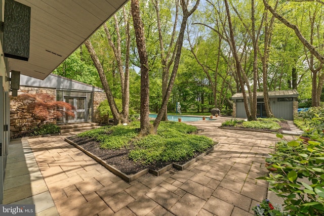 view of yard featuring a patio area, an outdoor pool, and an outbuilding