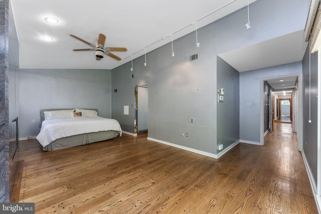 bedroom featuring wood finished floors, a high ceiling, baseboards, and a ceiling fan