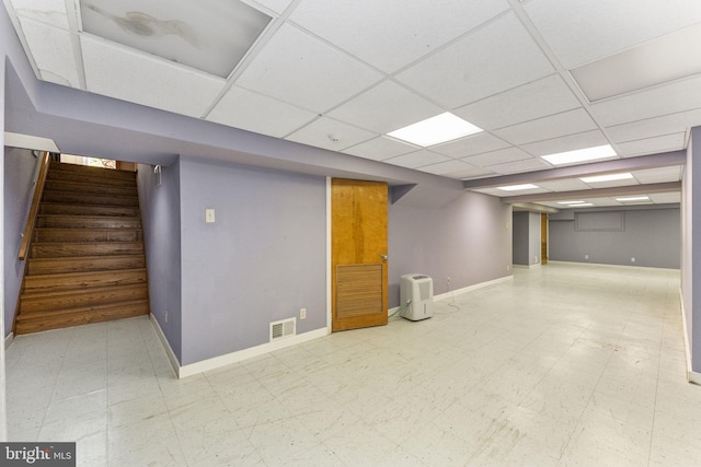 finished below grade area with stairway, tile patterned floors, baseboards, and a drop ceiling