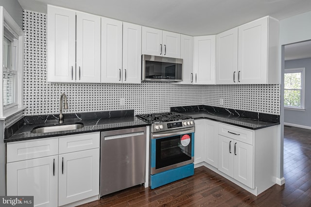 kitchen with a sink, dark stone countertops, stainless steel appliances, and dark wood finished floors