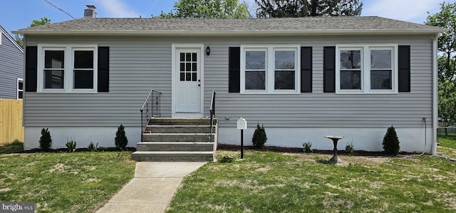 view of front facade featuring fence, a chimney, and a front lawn