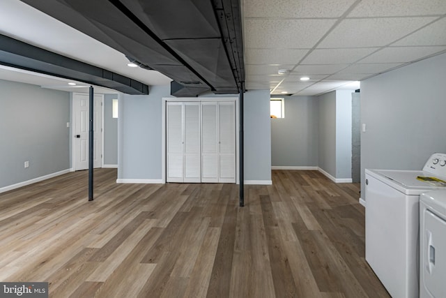 basement with baseboards, washing machine and dryer, and wood finished floors