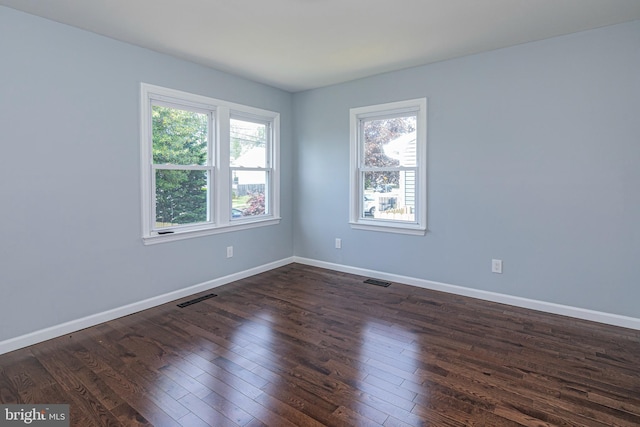 spare room with baseboards, dark wood finished floors, and visible vents