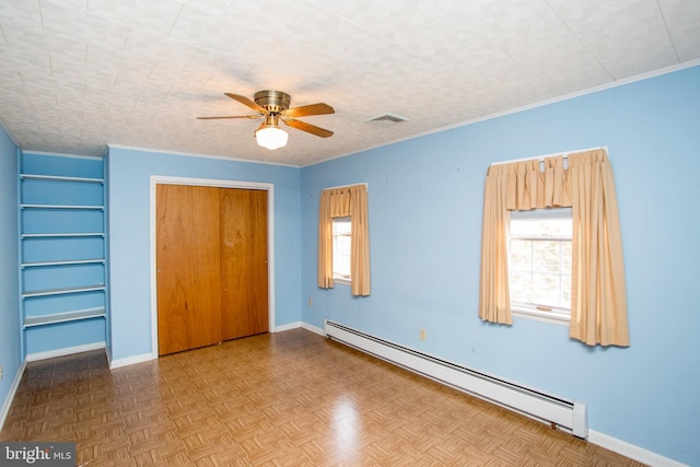 unfurnished bedroom with baseboard heating, baseboards, visible vents, ornamental molding, and a closet