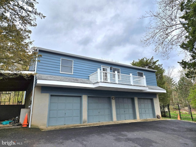 view of front facade with driveway, fence, a balcony, an attached garage, and stucco siding
