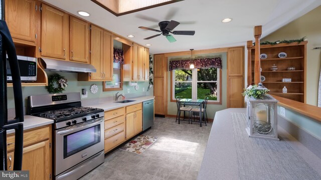 kitchen with stainless steel appliances, a sink, under cabinet range hood, light countertops, and a ceiling fan