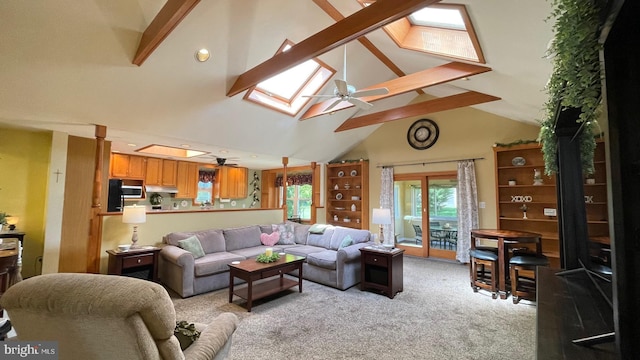 living room featuring a ceiling fan, a skylight, light colored carpet, beamed ceiling, and high vaulted ceiling