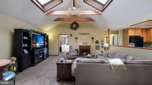 living area with a skylight, light colored carpet, lofted ceiling, a ceiling fan, and a warm lit fireplace