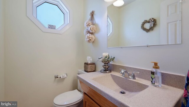 half bathroom with vanity and toilet