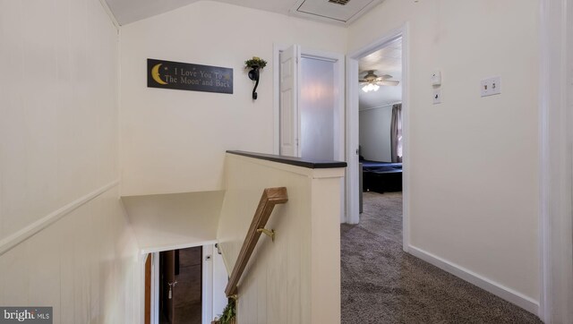 hallway with an upstairs landing, carpet flooring, and lofted ceiling