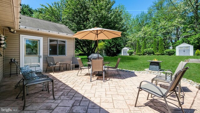 view of patio / terrace featuring a storage shed, outdoor dining area, and an outbuilding