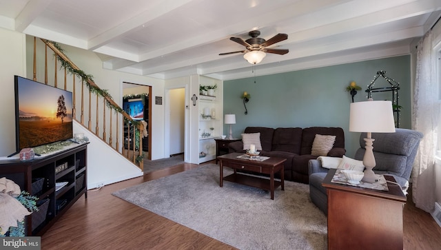 living room with stairs, beamed ceiling, wood finished floors, and a ceiling fan