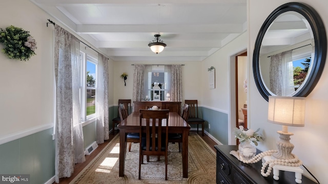 dining room with beam ceiling and wood finished floors