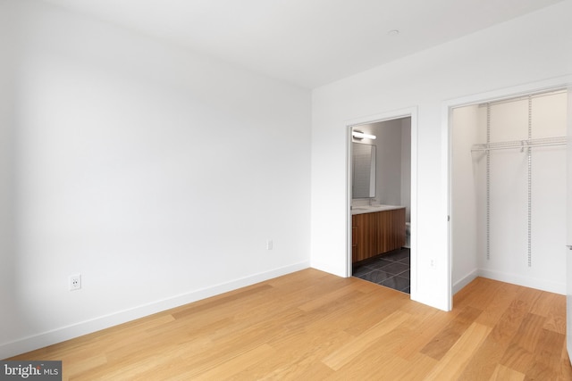 7175 12th St NW Unit 506, Washington, DC 20011 - unfurnished bedroom featuring baseboards, wood finished floors, ensuite bathroom, and a closet