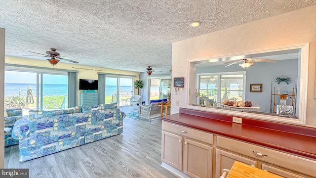living room with light wood-style floors, a ceiling fan, recessed lighting, and a textured ceiling