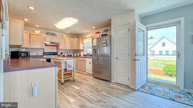 kitchen with a textured ceiling, light brown cabinetry, under cabinet range hood, light wood-style floors, and stainless steel appliances