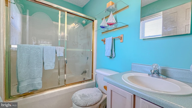 bathroom featuring vanity, combined bath / shower with glass door, and toilet