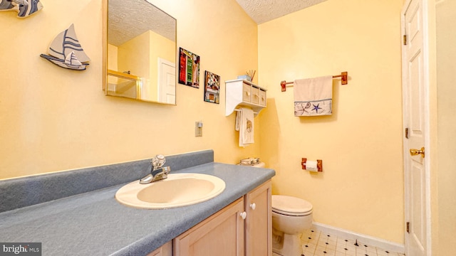 bathroom with a textured ceiling, vanity, baseboards, tile patterned floors, and toilet