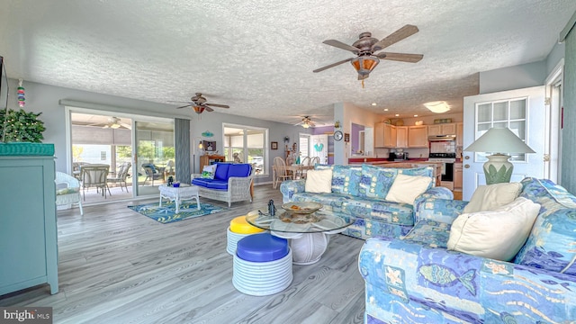 living room featuring light wood-style floors, a textured ceiling, and ceiling fan