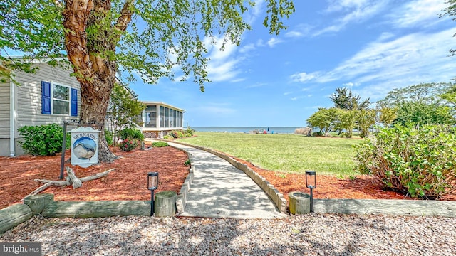 view of yard with a sunroom and a water view