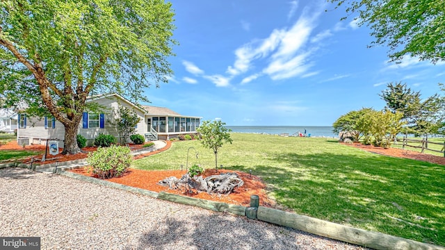 view of yard with a sunroom, a water view, and fence