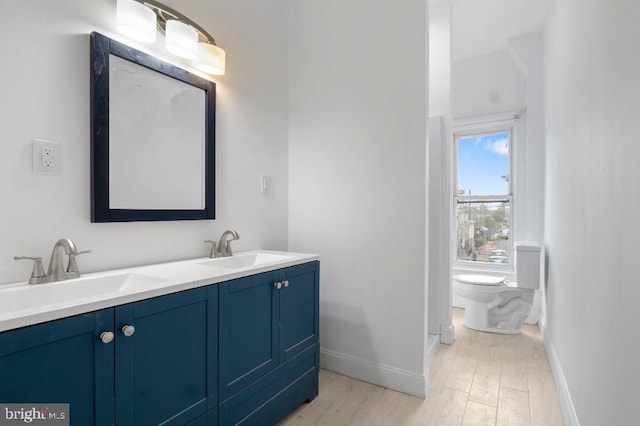 bathroom with a sink, baseboards, toilet, and wood finished floors