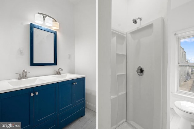 full bath with a sink, double vanity, toilet, and a shower