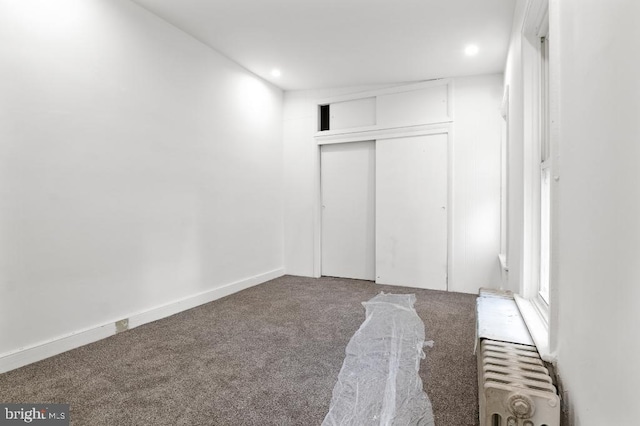 unfurnished bedroom featuring carpet floors, recessed lighting, radiator heating unit, and a closet