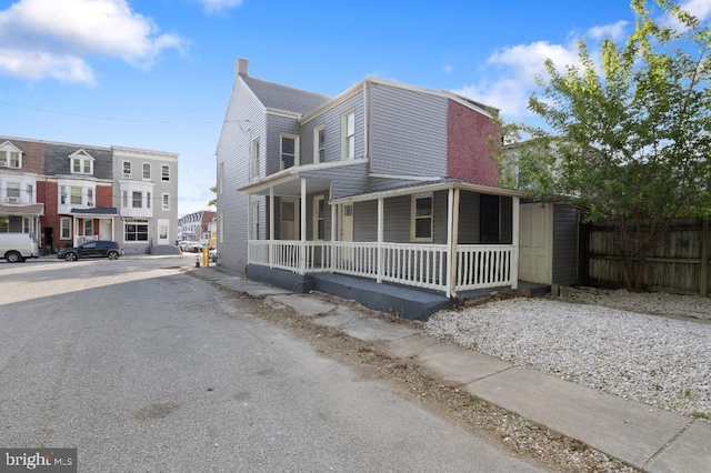 view of front of house featuring fence, a chimney, and a porch
