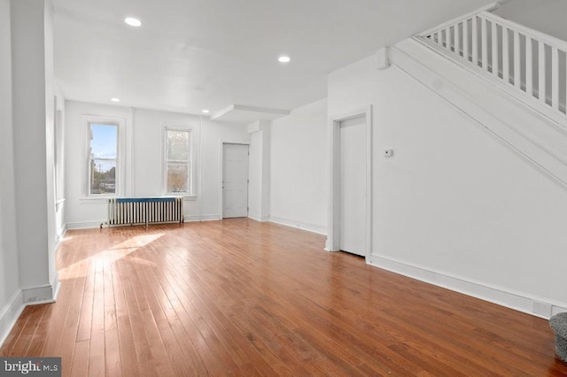 unfurnished living room featuring recessed lighting, baseboards, radiator, and hardwood / wood-style floors