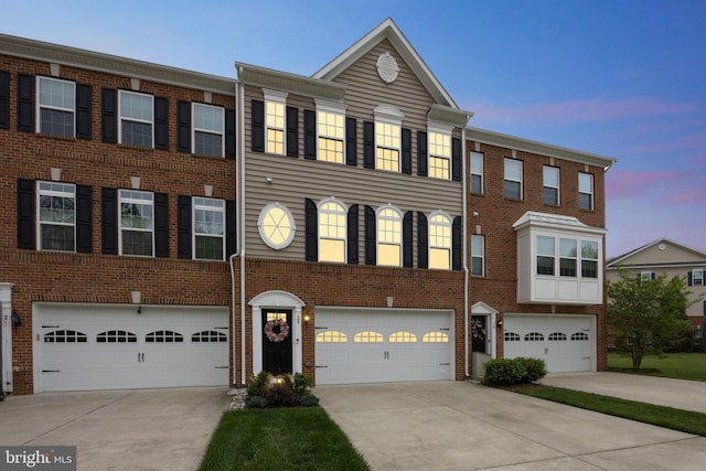 view of property featuring driveway, brick siding, and an attached garage