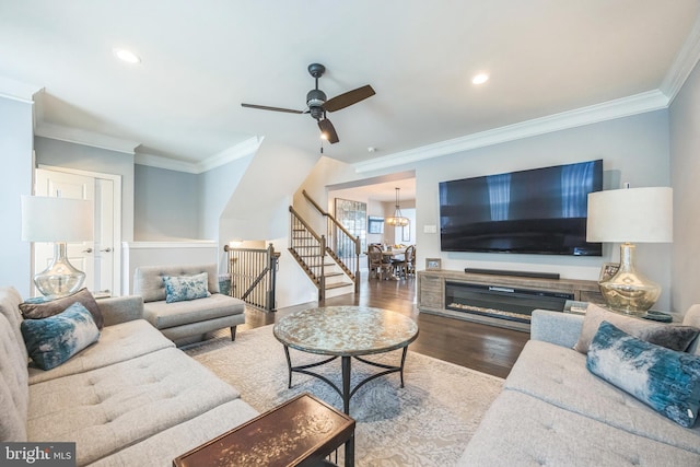 living room with ornamental molding, ceiling fan with notable chandelier, recessed lighting, and wood finished floors