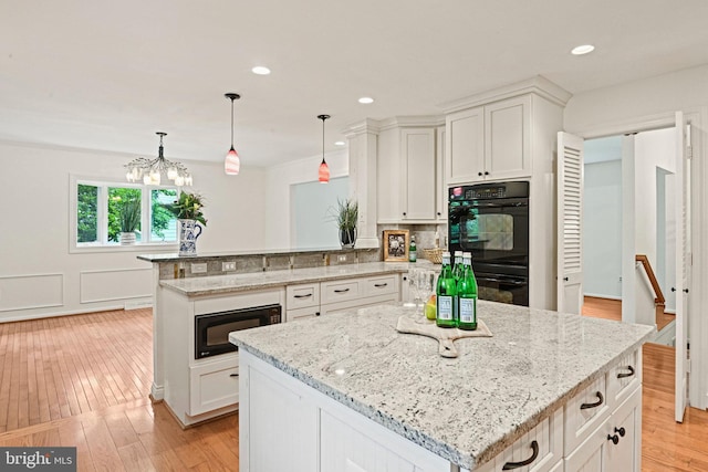 1716 Saddle Ridge Ct, Vienna, VA 22182 - kitchen featuring black appliances, a peninsula, light stone counters, white cabinetry, and a kitchen island