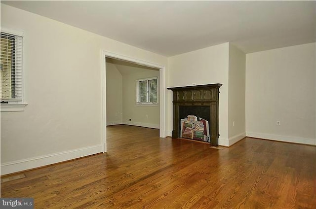 unfurnished living room with baseboards, a fireplace, and wood finished floors