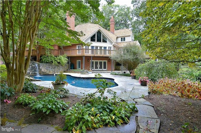 rear view of property with french doors, a chimney, a patio area, and an outdoor pool