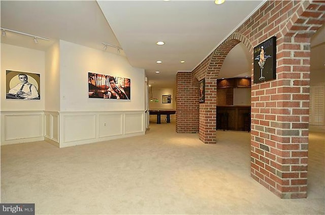interior space featuring carpet floors, rail lighting, and a wainscoted wall