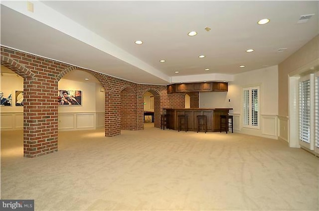 interior space with arched walkways, a decorative wall, and light colored carpet