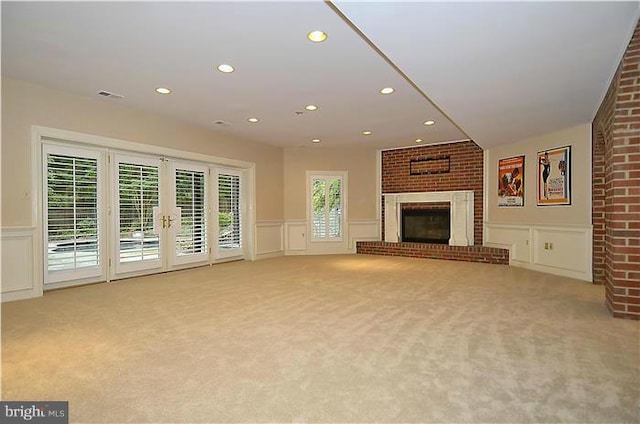 unfurnished living room with a wainscoted wall, light carpet, and a decorative wall