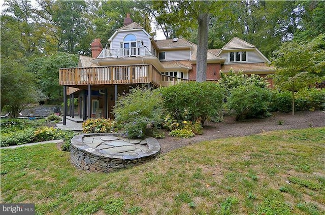 rear view of property with a lawn, a chimney, a deck, and a balcony