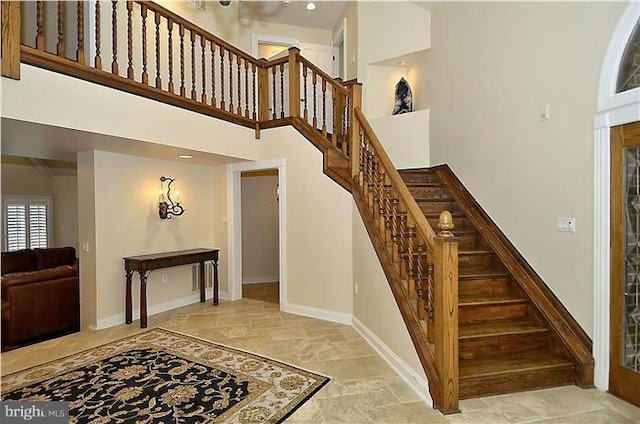 stairs with baseboards and a towering ceiling