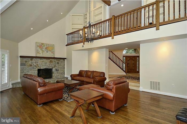 living area with high vaulted ceiling, a fireplace, wood finished floors, and visible vents