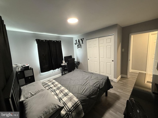 bedroom featuring baseboards, wood finished floors, and a closet