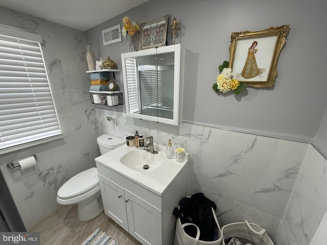 bathroom featuring toilet, tile walls, and vanity