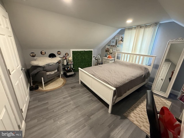bedroom with wood finished floors and lofted ceiling