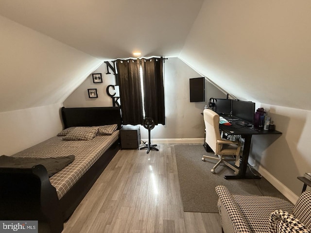 bedroom featuring baseboards, vaulted ceiling, and wood finished floors