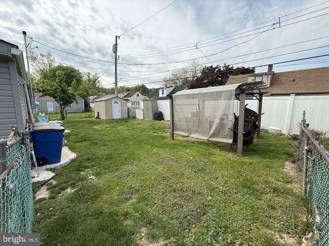 view of yard featuring a storage unit, fence, an outbuilding, and a residential view