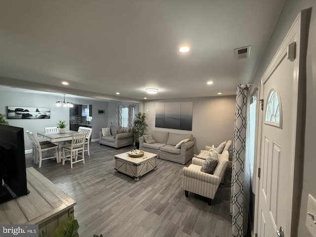 living area with visible vents, light wood-type flooring, baseboards, an inviting chandelier, and recessed lighting
