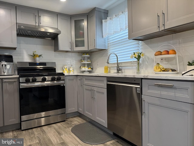 kitchen featuring a sink, gray cabinets, stainless steel appliances, and under cabinet range hood